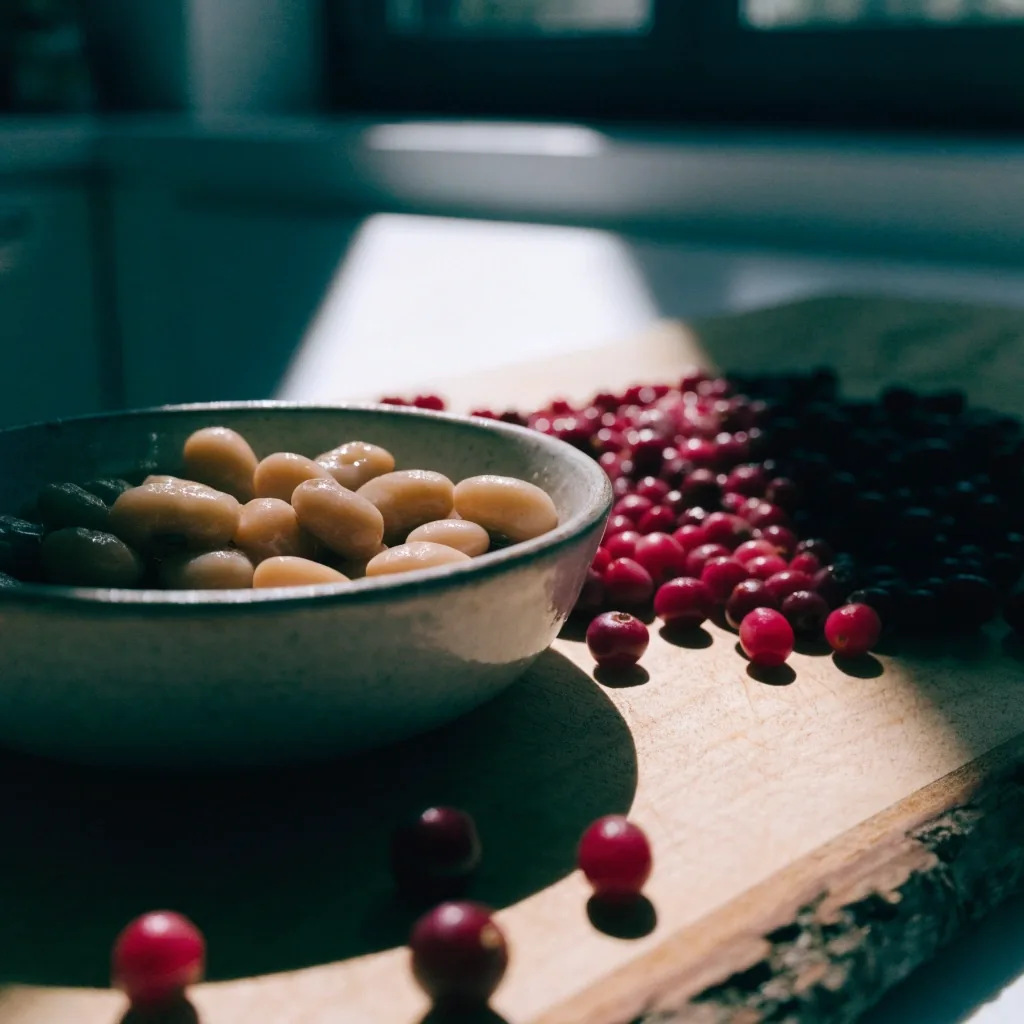 Soaked butter beans in a stoneware bowl with lingonberries on a birch board